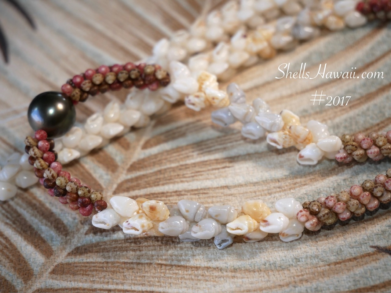 Traditional Niʻihau shell lei featuring a natural Tahitian pearl centerpiece with Momi and Kahelelani shells in a Kipona style design.