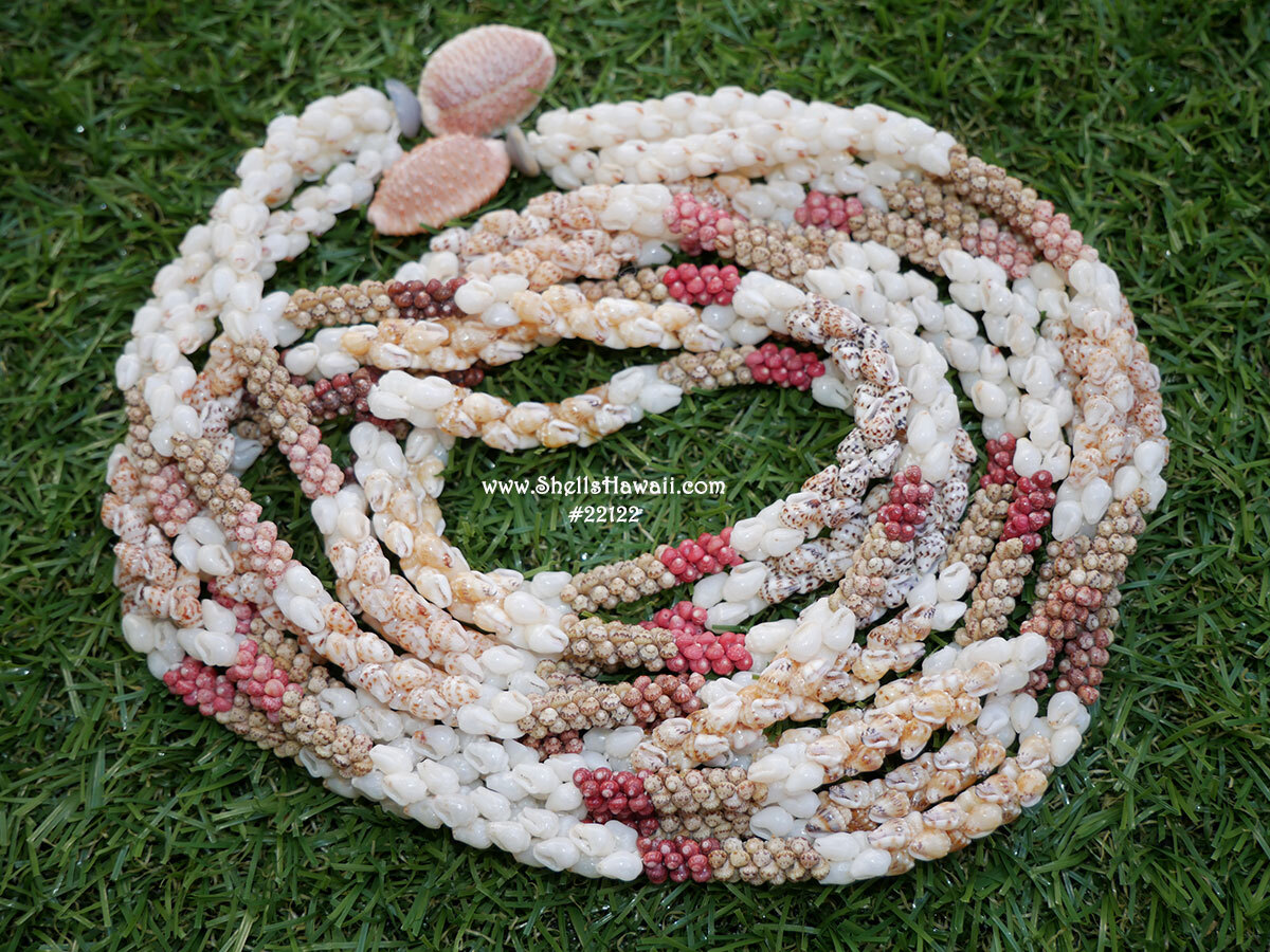 Authentic Niʻihau shell leis displayed on green grass, featuring handcrafted Hawaiian shell jewelry made with rare colors of Momi and Kahelelani shells in traditional 42 1/2" triple-strand Kipona styles. This image represents the deeper meaning behind Niʻihau shell jewelry discussed in this blog &mdash; how a piece can begin as a souvenir or luxury gift from Hawaiʻi and eventually become a treasured family heirloom passed down through generations.