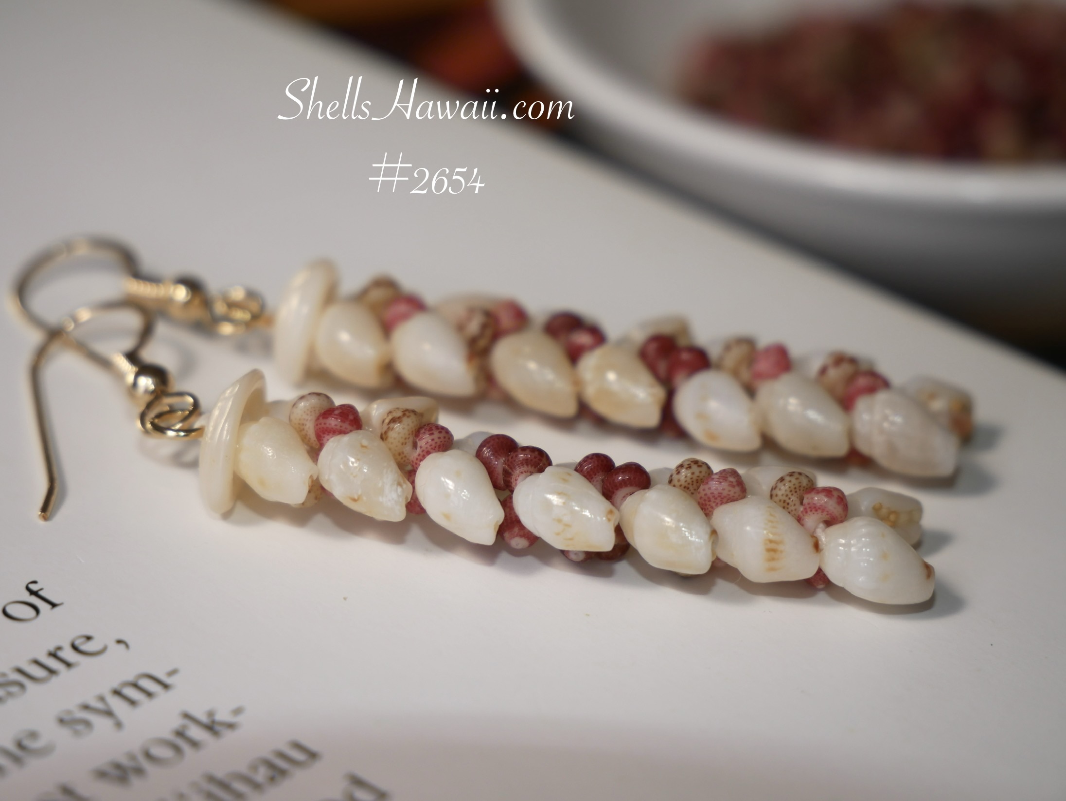 Close-up of Niʻihau shell earrings crafted in Heleconia style using Momi and Kahelelani shells, highlighting varied poking angles and layered movement in Hawaiian shell jewelry