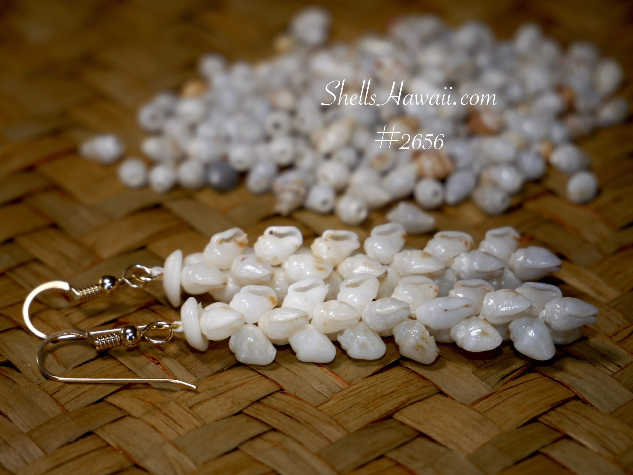 Single Pīkake style Niʻihau shell earrings made with Momi shells, showing a soft braided pattern with creamy off-white shells and natural variations displayed on a woven lauhala mat