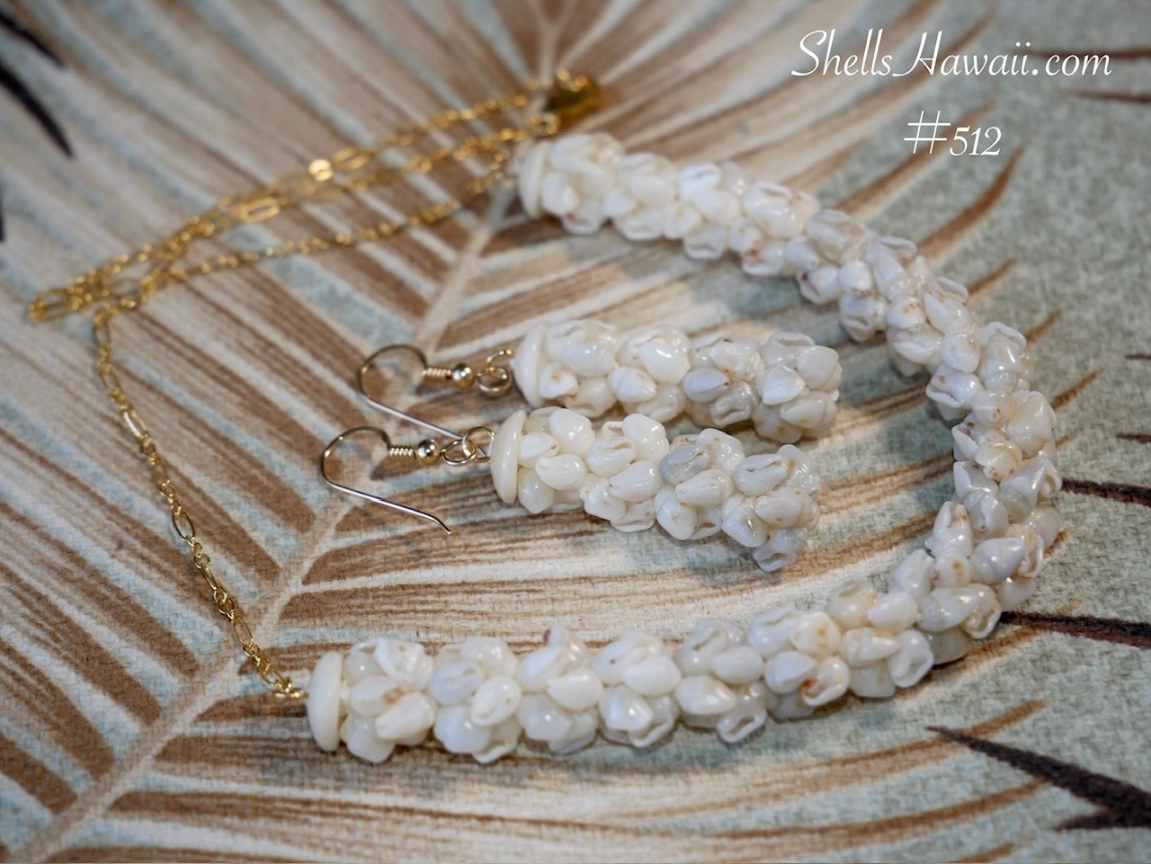 Close-up fuller rounded crown flower style necklace and earrings set featuring small-sized light blue ʻŪliʻuli and off-white Momi shells in a soft ombr&eacute; color flow. Modern Hawaiian shell jewelry with 14k gold filled chain showing puffier floral crown flower shellwork and soft natural color transition.