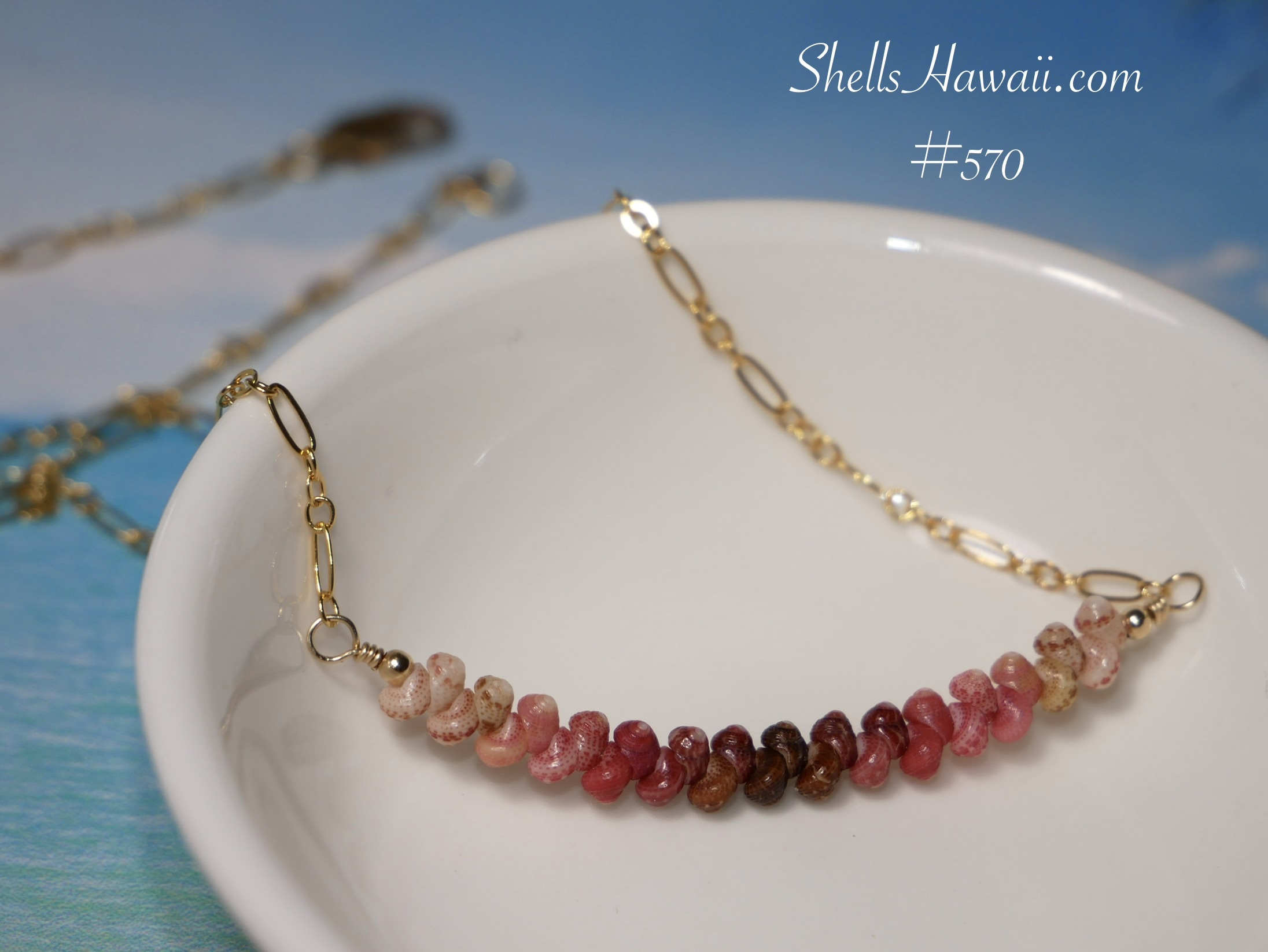 Full display of a minimalist Niʻihau Kahelelani shell necklace in rare ombré colors including black, brown, red burgundy, hot pink, pink flower, soft pink, soft green, and Keʻokeʻo, showing how tiny shell placement, wire wrapping techniques, patience, and attention to detail help create a clean, even, and effortless finished jewelry design.
