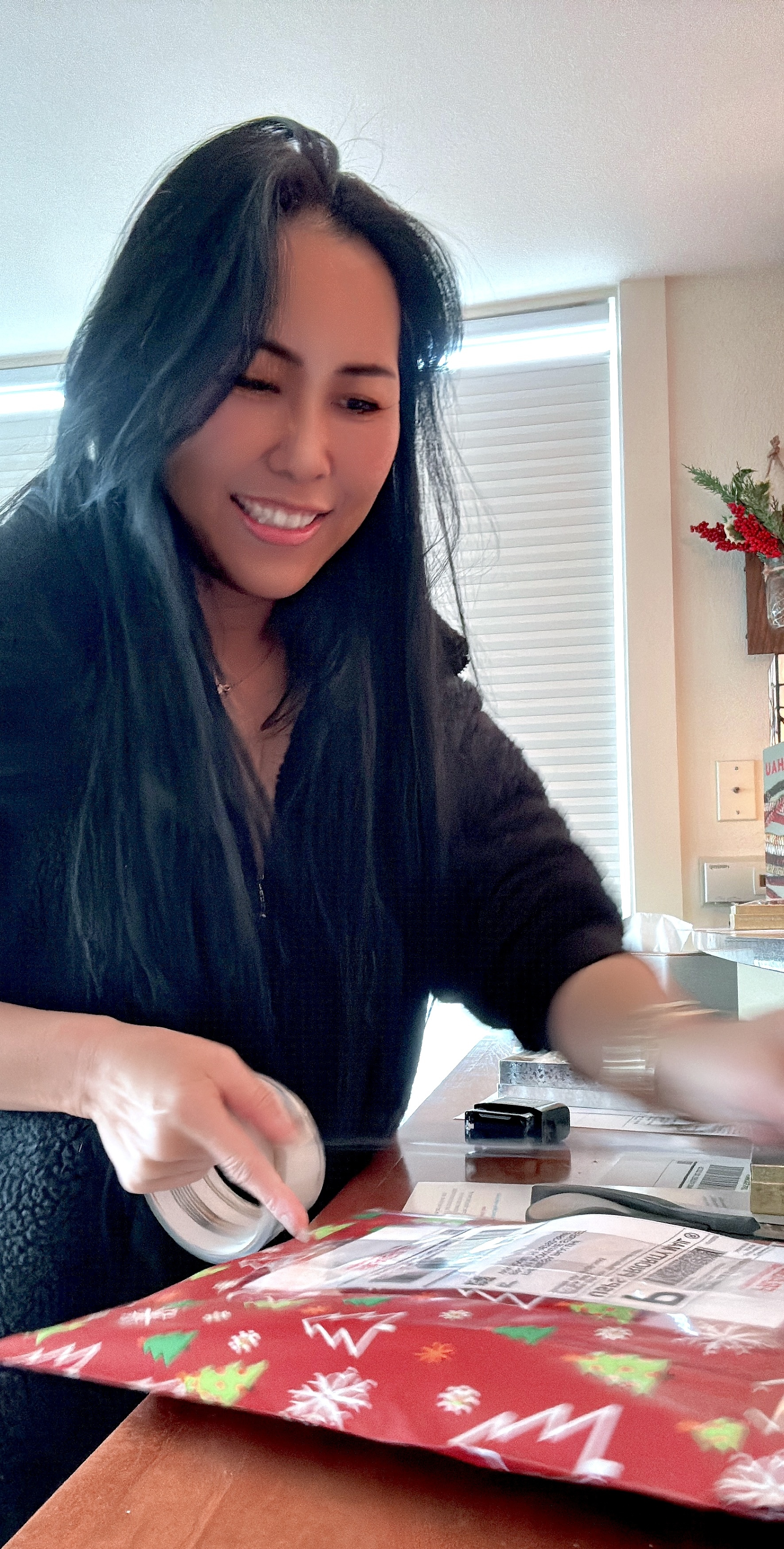 Packing Niʻihau shell jewelry orders during the holidays, carefully sealing gift packages by hand with festive wrapping and gratitude before shipping