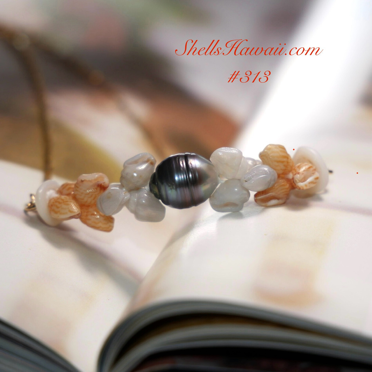 Niʻihau shell jewelry featuring light striped golden Momi Kahakaha ʻĀhiehie shells paired with soft white shells and a dark Tahitian pearl centerpiece