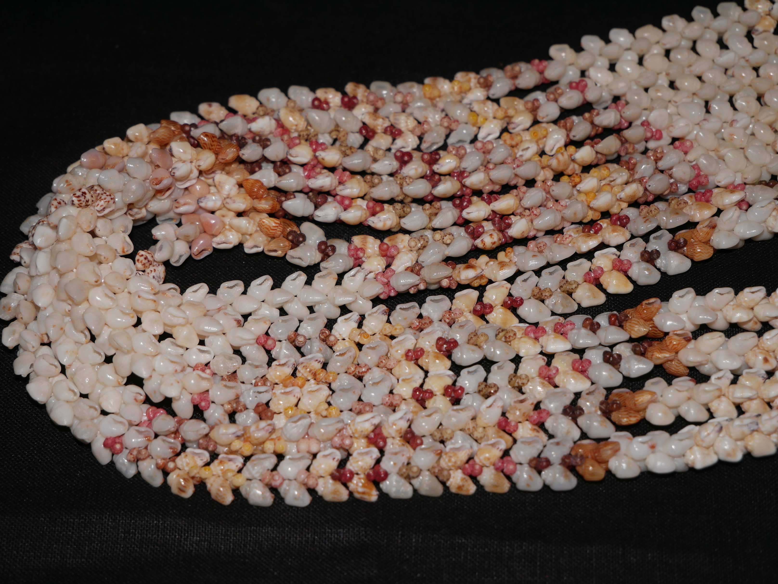 Close-up of Niʻihau shell lei in Heleconia style, highlighting the flowing pattern created by Momi and Kahelelani shells and showing how different poking angles guide the natural movement of Hawaiian shell jewelry