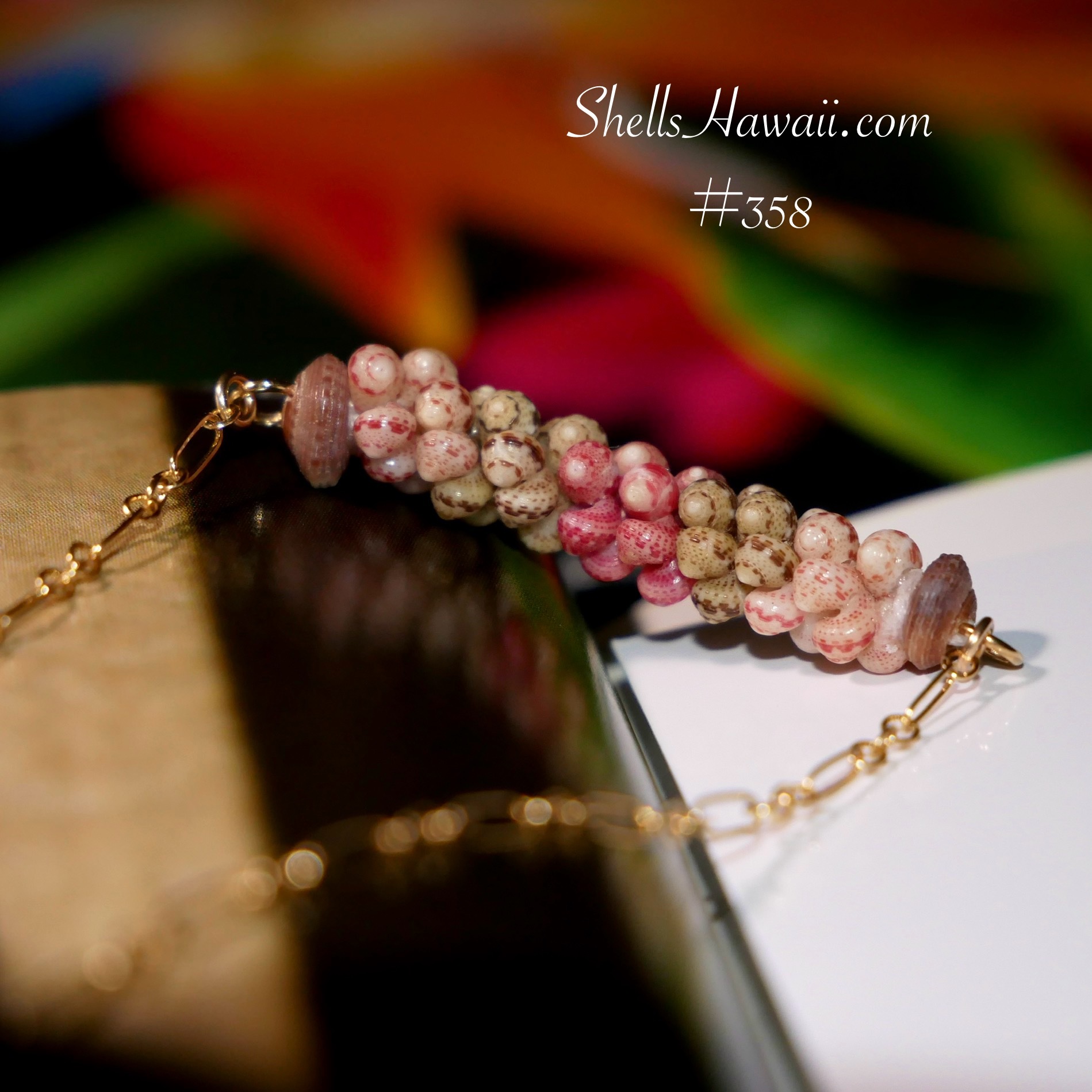 Close-up photograph of handcrafted minimalist pendant necklace in two-strand Poepoe style created with genuine Kahelelani shells from Niʻihau. The pendant features a visible square-shaped and stacked shell pattern with structured rows, showcasing natural shell colors including Keʻokeʻo white, ʻĀkala Pua pink flower, and ʻŌmaʻomaʻo green. Finished with delicate 14k gold filled chain accents and natural shell end caps.