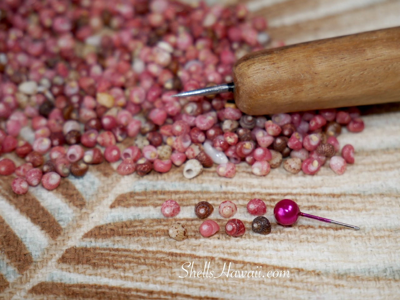 Kahelelani shells arranged by color tones for Niʻihau shell jewelry, showing pink flower, red, and burgundy shades selected for custom Kipona earrings with Poepoe design