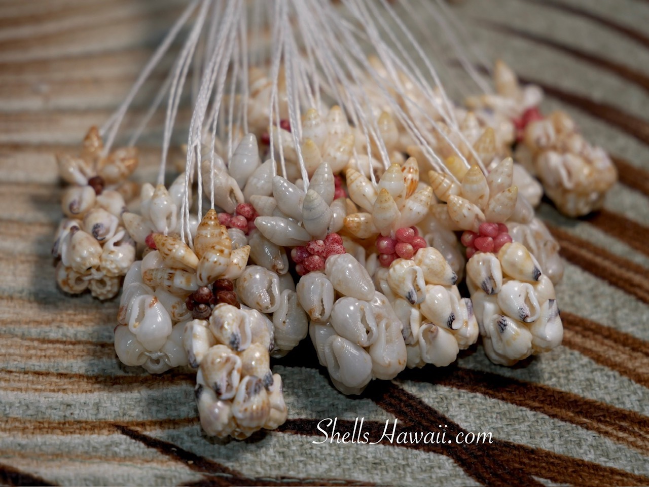 Niʻihau shell pineapple earrings in progress at pao hana time, multiple Momi, Laiki, and Kahelelani shell designs grouped together on work table, handmade Hawaiian shell jewelry before final finishing step