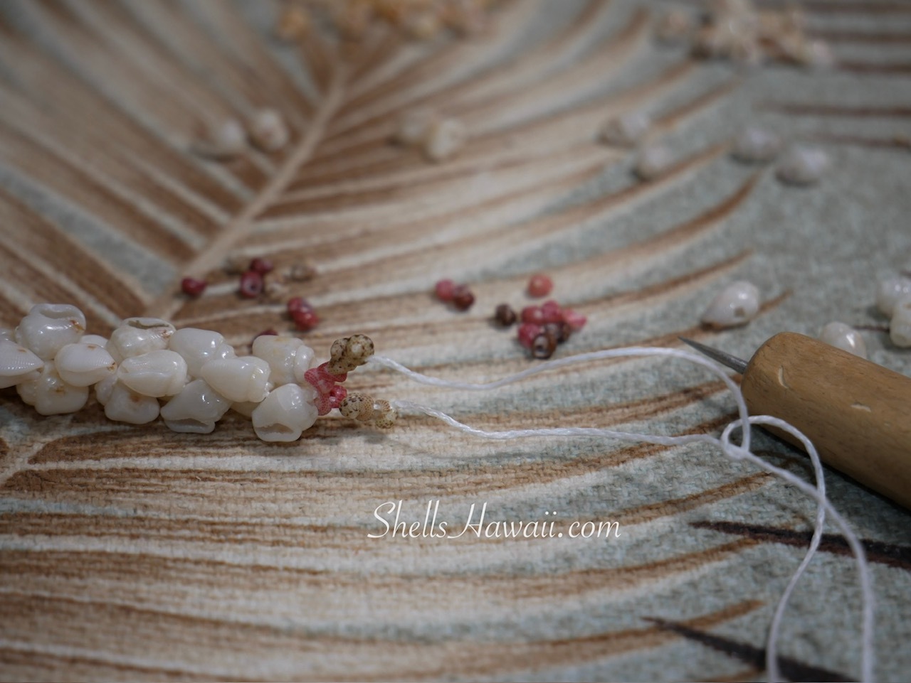 Undoing Niʻihau shell bracelet showing string becoming harder to work with when re-threading Momi and Kahelelani shells