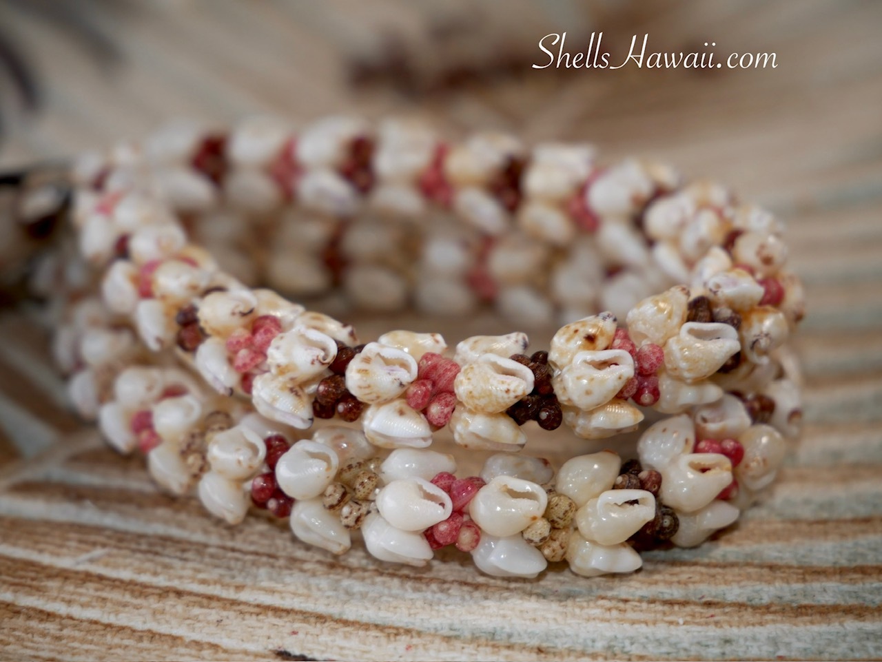 Close up of two handmade Kipona style shell bracelets stacked together, featuring carefully matched Momi and tiny size 10 Kahelelani shells from Niʻihau. The image highlights the balanced color flow, detailed shell matching, and fine workmanship created through careful placement of the shells in a traditional Hawaiian shell jewelry design.